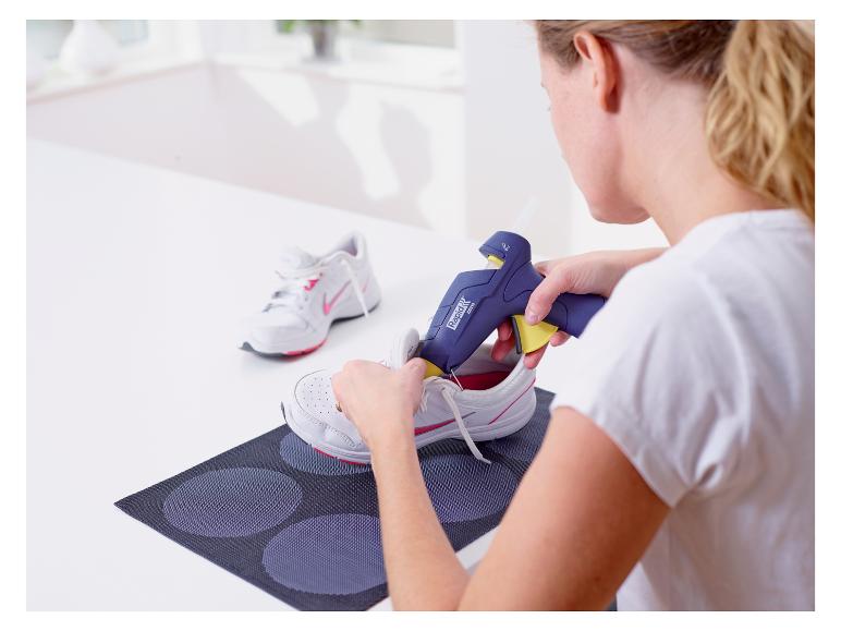 Femme utilisant un pistolet à colle LIVARNO® pour coller des baskets.