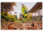 Un homme avec un souffleur à feuilles dans un jardin plein de feuilles.