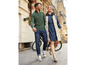 Un homme et une femme marchent à côté d'un vélo, il porte un pull vert et elle une robe en jean.
