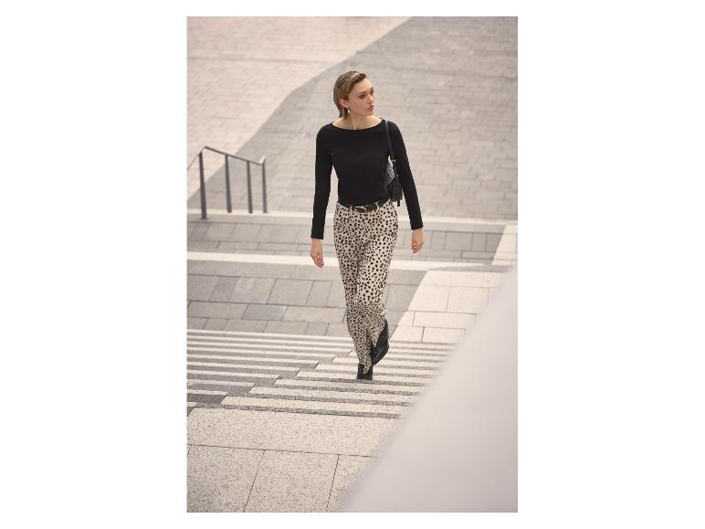 Femme en haut noir et pantalon imprimé léopard descendant des escaliers.