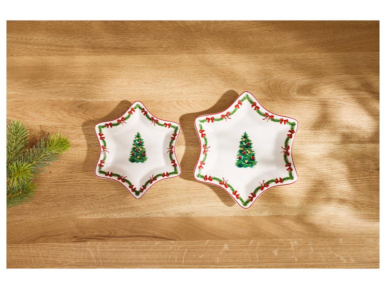 Deux assiettes blanches en forme d'étoile avec des décorations de Noël sur une table en bois.