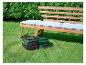 Robot tondeuse Parkside dans le jardin sous un banc en bois avec coussins.