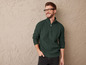 Un homme portant un pull vert et des lunettes.