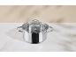 Casserole en acier inoxydable avec couvercle en verre sur une surface en marbre blanc.