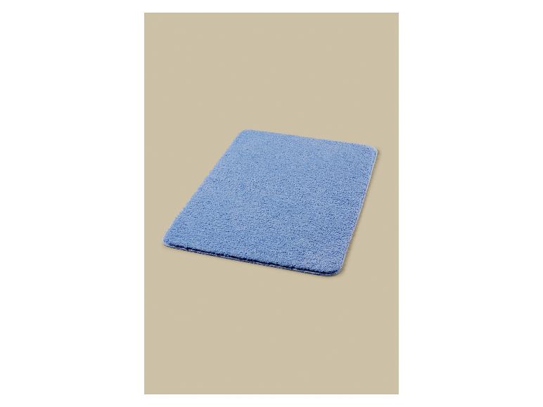 Tapis de bain bleu sur fond beige.
