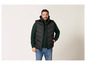 Un homme portant un gilet matelassé noir, un sweat-shirt à capuche vert et un jean bleu.