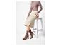 Femme en bottes marron et jupe beige assise sur un tabouret blanc.