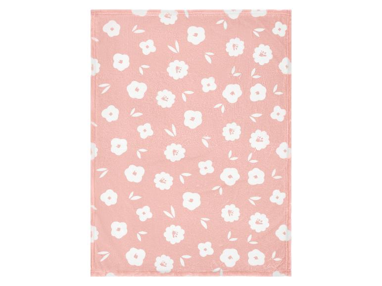 Couverture rose avec un motif de fleurs et de feuilles blanches.