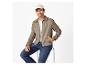 Homme en veste beige, t-shirt blanc, jean et casquette beige, assis sur un tabouret.