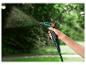 Un tuyau d'arrosage vert avec un pistolet de pulvérisation Parkside, arrosant un jardin.