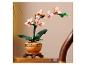 Orchidée jouet en pot avec des fleurs roses et des feuilles vertes, sur une table en bois.