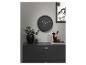 Horloge murale noire, vase, plantes et accessoires de bureau sur un meuble gris foncé.