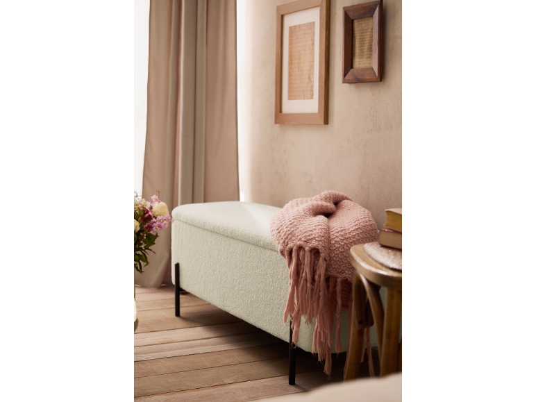 Banc rembourré avec une couverture rose dans un cadre douillet avec rideaux et tableaux.