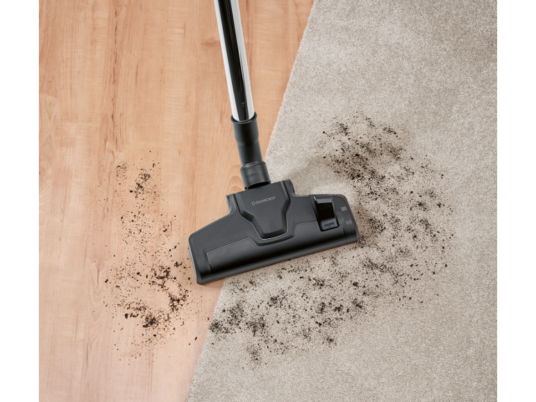 Aspirateur sur parquet et tapis avec de la saleté.