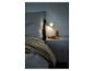 Un lit avec une couette, une table de chevet avec un livre et une lampe Philips Hue.