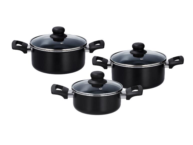 Trois casseroles noires avec couvercles en verre et poignées noires.
