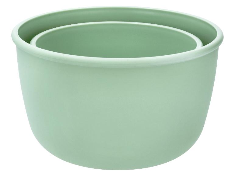 Deux pots de fleurs en plastique verts, l'un emboîté dans l'autre.