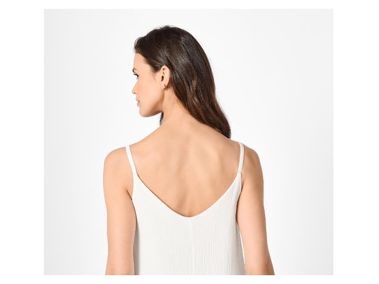 Femme aux cheveux foncés et débardeur blanc à fines bretelles, vue de dos.