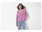 Une femme porte un cardigan rose à boutons et un jean bleu.