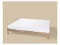 Lit en bois avec matelas blanc sur fond beige.