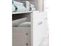 Commode blanche avec tiroirs et une étagère pour vêtements de bébé.