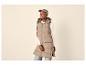 Femme en longue doudoune beige, pull blanc et jean, portant une casquette grise.