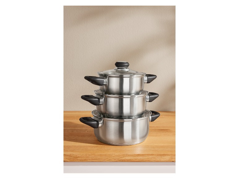 Trois casseroles empilées en acier inoxydable avec couvercles en verre.