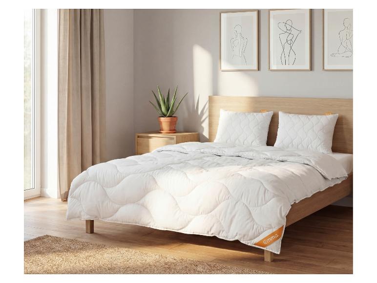 Chambre avec lit en bois, couette et oreillers blancs, à côté d'une fenêtre avec rideaux.