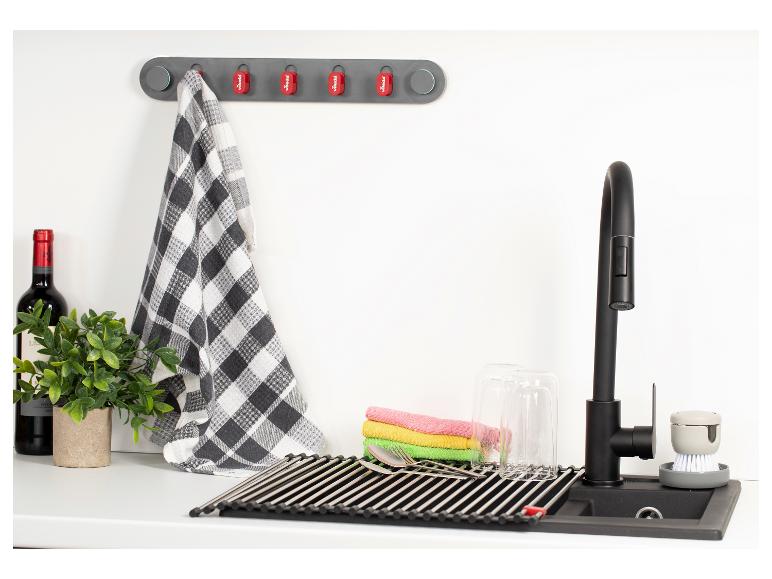 Évier de cuisine avec égouttoir, serviettes et brosse de nettoyage.