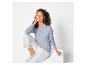 Une femme portant un pull bleu et un pantalon blanc.