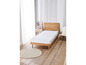 Un matelas blanc sur un cadre de lit en bois dans une chambre claire.