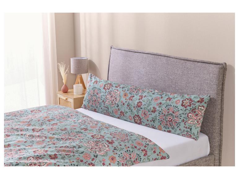 Un lit avec une tête de lit grise, une couette à fleurs et un oreiller.
