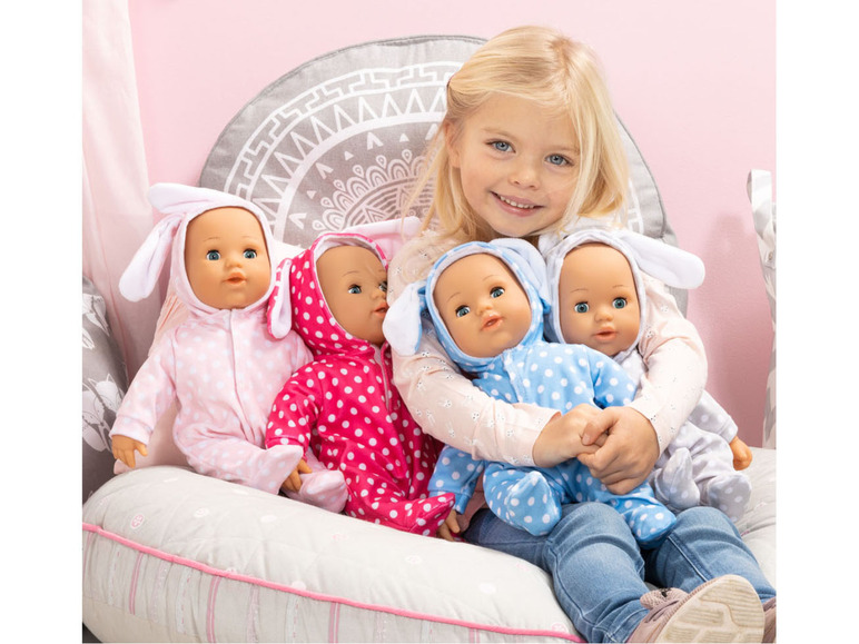 Une fille tient quatre poupées, toutes habillées en pyjamas de lapin.