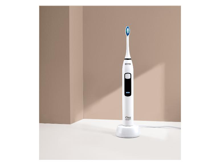 Brosse à dents électrique blanche avec base de chargement sur fond beige.
