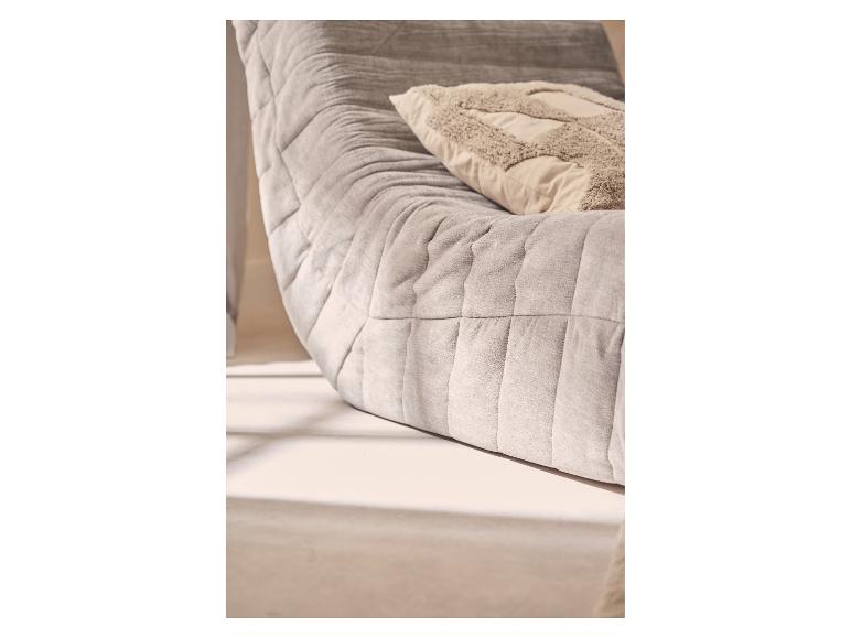 Canapé matelassé gris avec coussin décoratif beige.