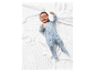 Bébé souriant en pyjama à pois sur une couverture blanche.