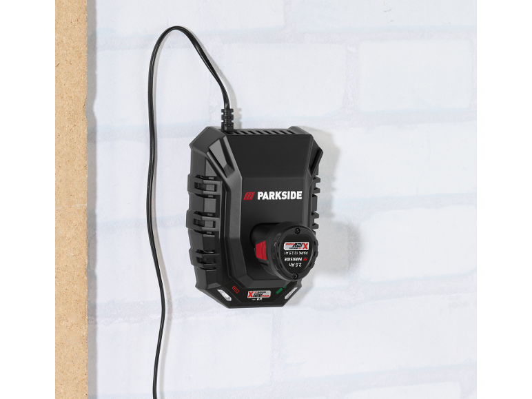Chargeur de batterie avec une batterie de 2,5 Ah fixé à un mur blanc.