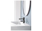 Un robinet de lavabo noir avec un lavabo dans une salle de bain avec un miroir rond.
