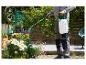 Une personne arrose des plantes dans le jardin avec un pulvérisateur Gardena.