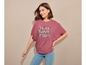 Une femme porte un t-shirt rose avec l'inscription 'Think Happy Thoughts' et un jean bleu.
