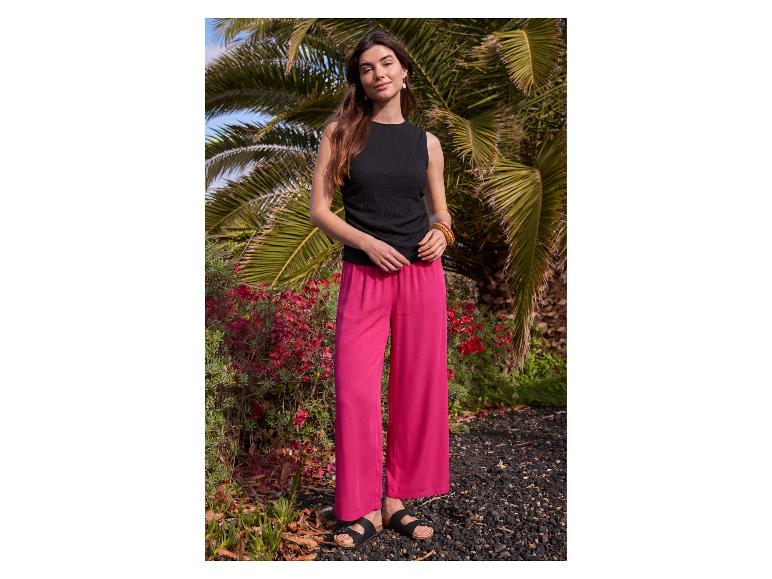 Femme en débardeur noir et pantalon large fuchsia.