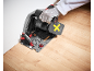 Personne coupant des planches de parquet en bois avec une scie plongeante, portant des gants de protection.