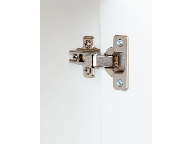 Une charnière argentée fixée à une porte d'armoire blanche.