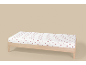 Drap-housse blanc à cœurs rouges sur un lit en bois.