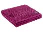 Serviette de bain magenta pliée avec un motif texturé et une étiquette noire.