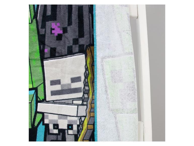 Serviette de bain avec motif squelette et éléments verts, suspendue à un porte-serviettes blanc.