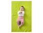 Bébé en haut blanc à manches longues et pantalon rose allongé sur une couverture verte.