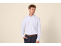 Homme en chemise blanche classique à manches longues et pantalon foncé.