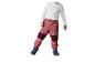 Enfant en chemise blanche et pantalon rose avec des bottes bleu foncé.