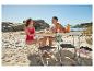 Couple sur la plage avec table pliante, fruits et bouteille d'eau.